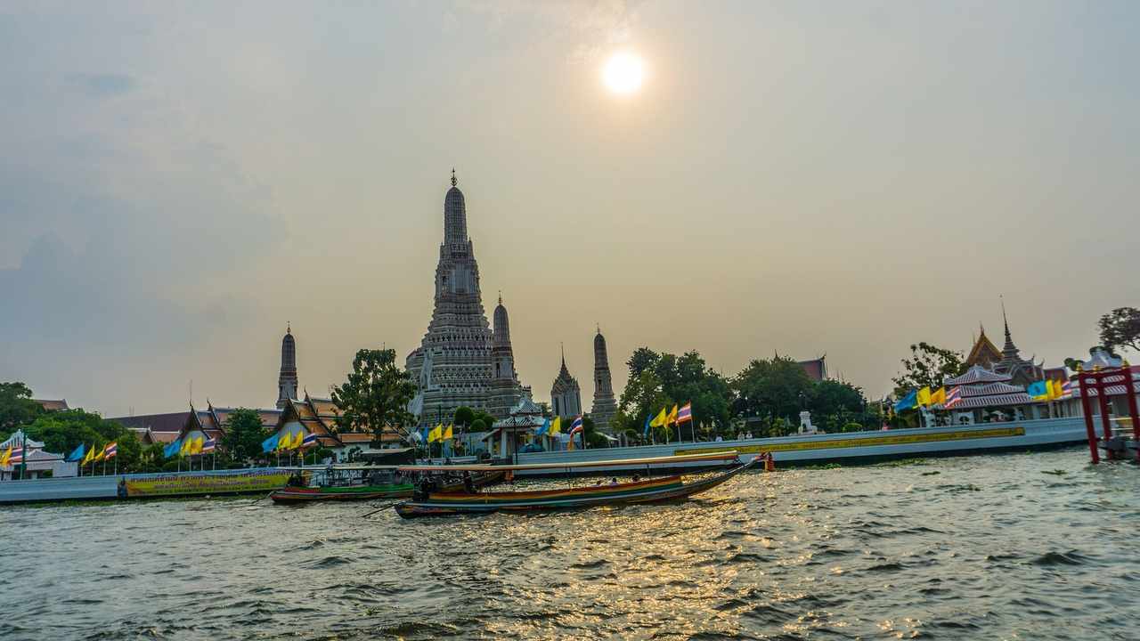 Wat Arun temple across the Chao Phraya River at sunset in Bangkok — Thailand country profile hero image