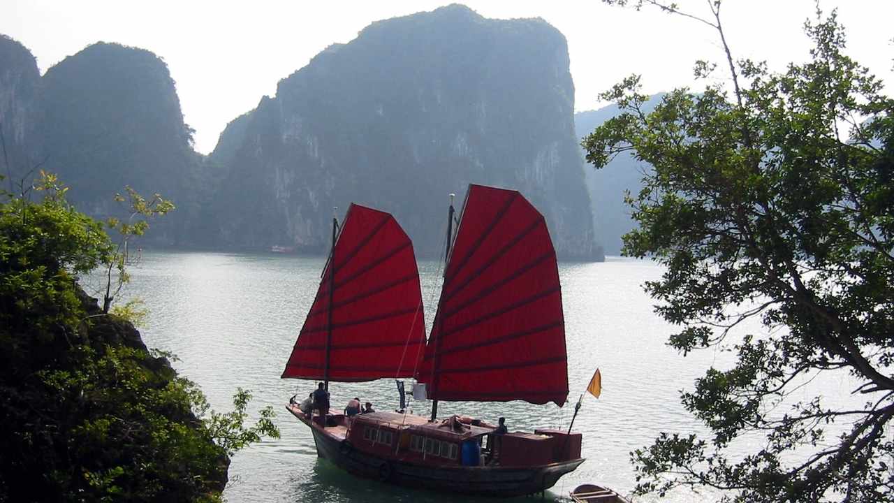 Traditional junk boat sailing between limestone islands in Ha Long Bay — Vietnam eVisa guide
